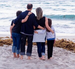 Family group on beach with arms around each other