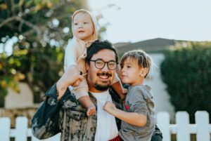 Smiling man carrying two small children