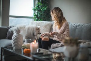 woman at home on soft with little white dog