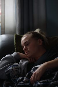 woman led on sofa with eyes closed asleep, napping