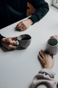 two cups of tea on table hands holding them